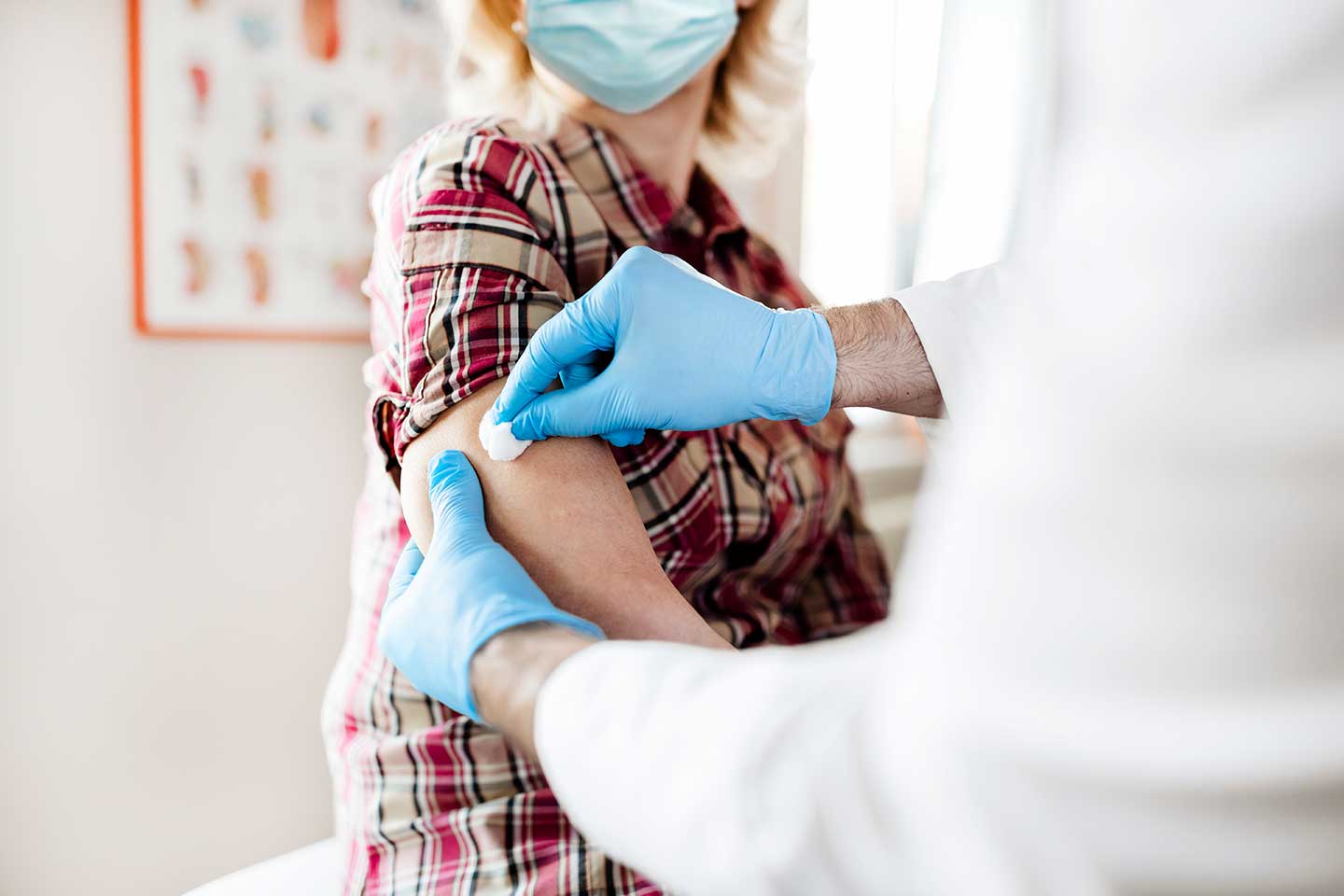 Doctor preparing woman's arm for vaccine