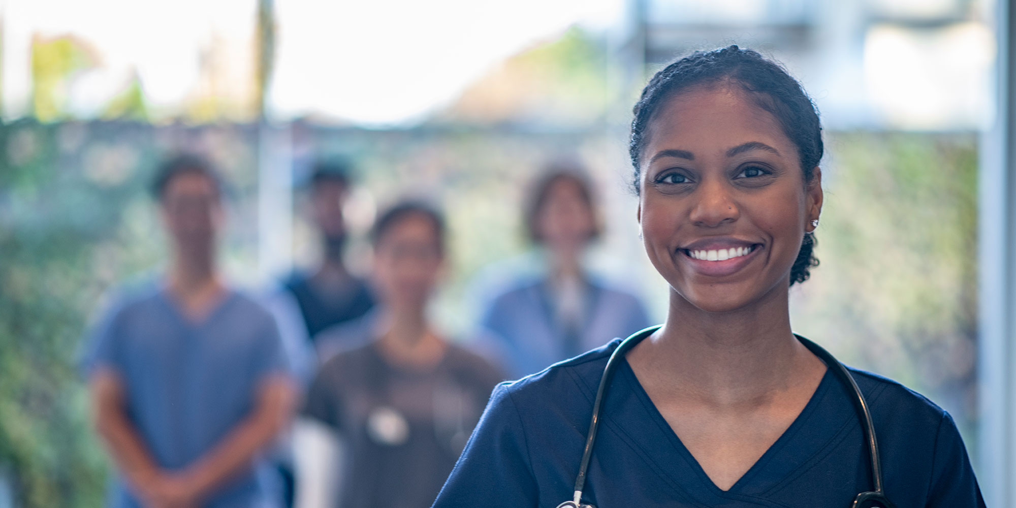 A group of residents stand together in a hospital, smiling at the camera