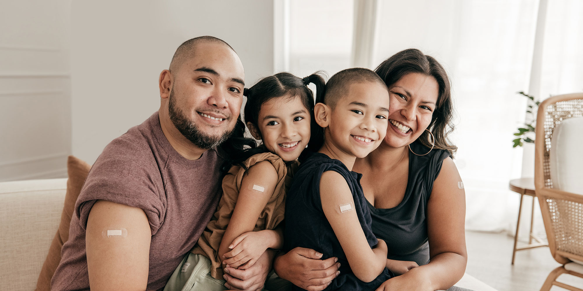 A family of four shows off their arms where they received the COVID-19 vaccine