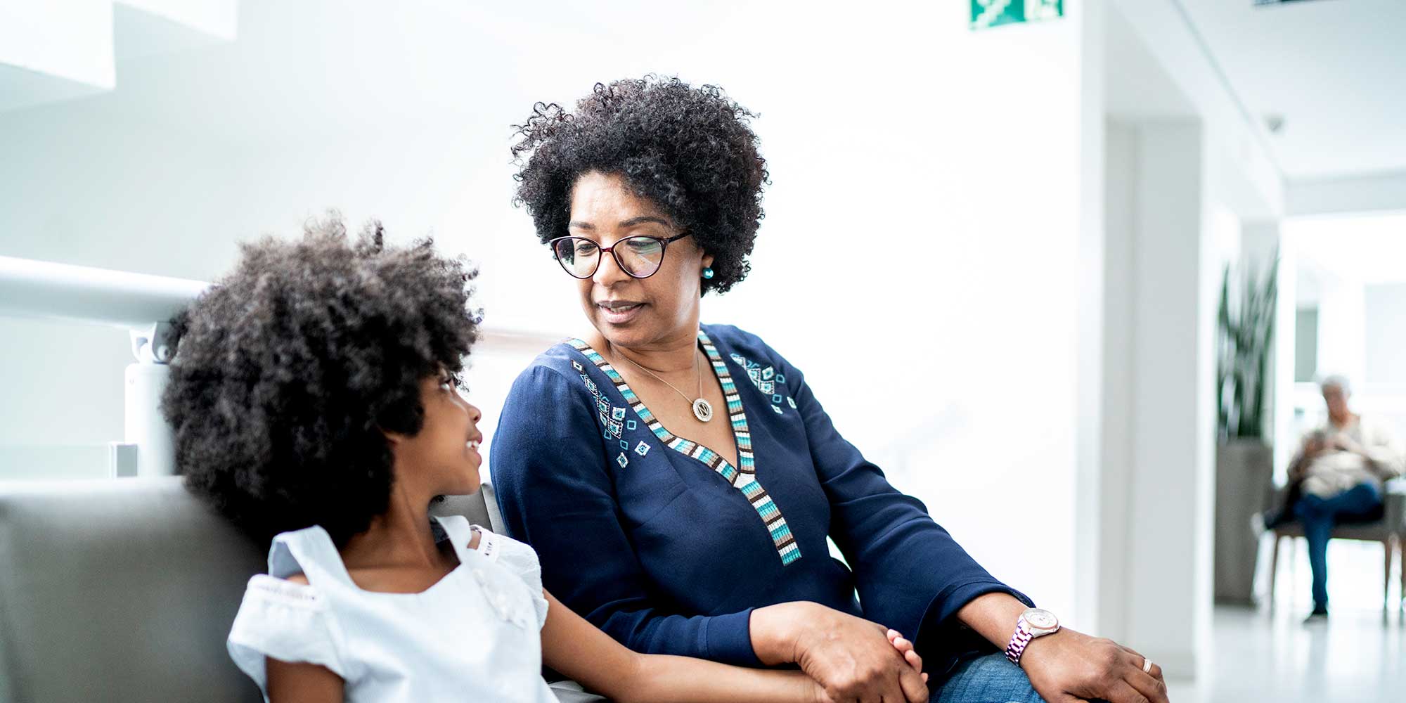 A mother and daughter sit in a hospital waiting room